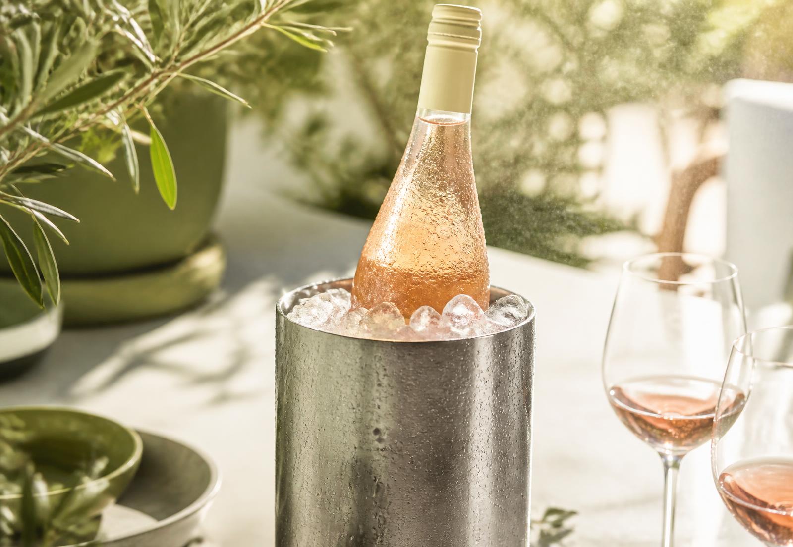 Bouteille de rosé glacée dans un rafraîchisseur inox, condensation et brume fine au soleil